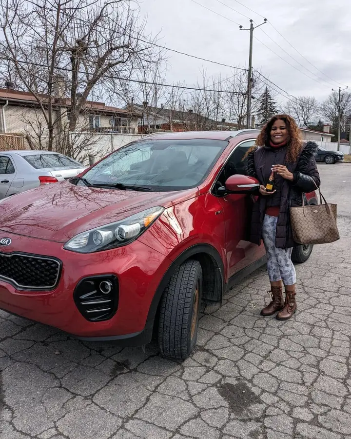 Cliente devant son Kia Sportage rouge vendu à En Ligne Autos